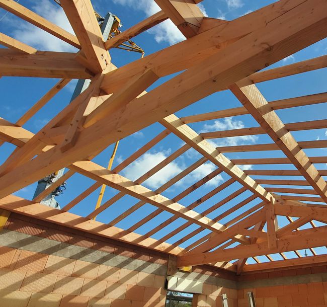Artisan SF Toiture installant une nouvelle charpente en bois lors d'un chantier d'arasement sur une maison traditionnelle dans la Loire